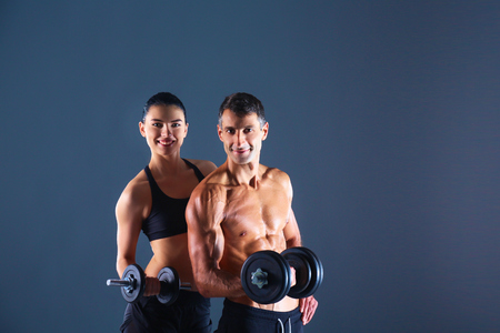 Athletic man and woman with a dumbells.の写真素材
