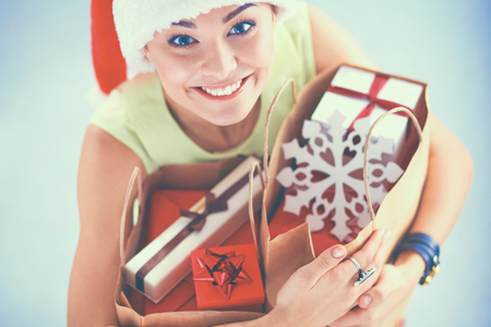 Smiling woman in santa hat with many gift boxes on white background.の写真素材