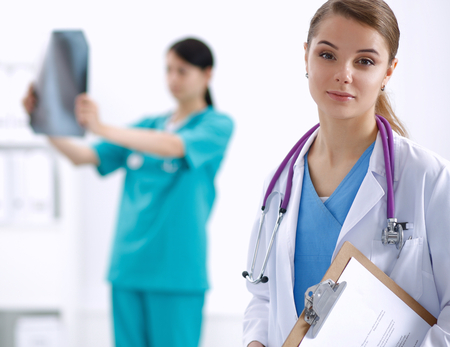 Woman doctor standing with folder at hospital.の写真素材