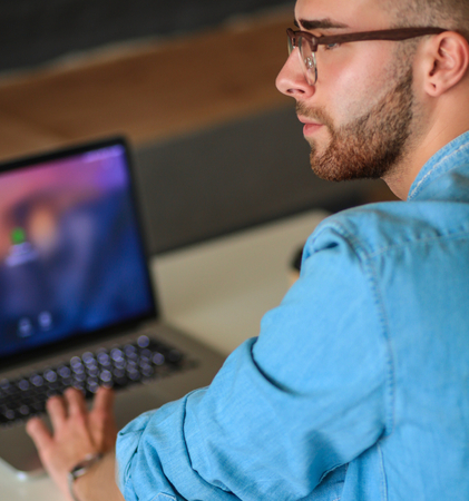 Young man works with laptop sitting on sofa.の写真素材