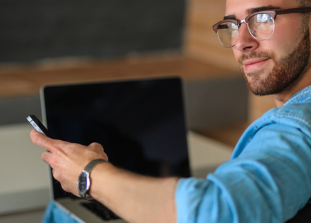 Young man works with laptop sitting on sofa.の写真素材