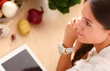 Young woman using a tablet computer to cook in her kitchen .の写真素材