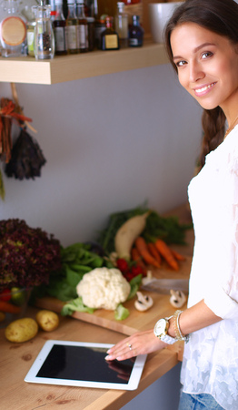 Young woman using a tablet computer to cook in her kitchen .の写真素材