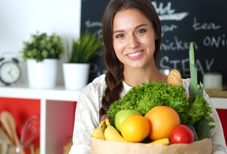 Young woman holding grocery shopping bag with vegetablesの写真素材