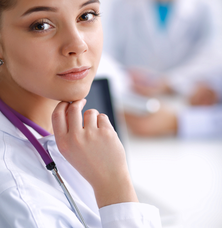 Beautiful young smiling female doctor sitting at the desk.の写真素材