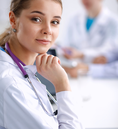 Beautiful young smiling female doctor sitting at the desk.の写真素材