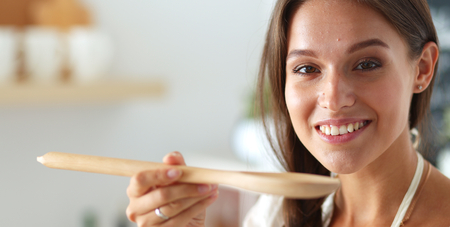 Cooking woman in kitchen with wooden spoonの写真素材