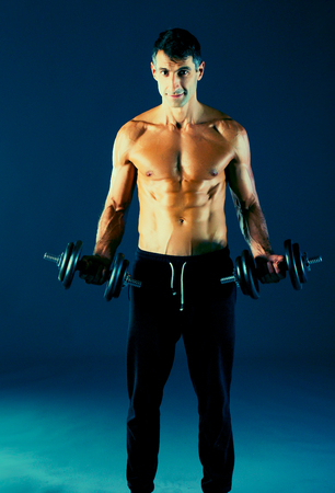 Handsome muscular man working out with dumbbells.の写真素材