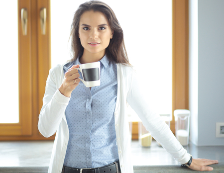 happy woman drinking tea in the kitchen at homeの写真素材