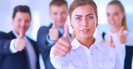 Happy business team showing thumbs up in office.の写真素材