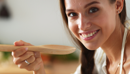 Cooking woman in kitchen with wooden spoonの写真素材