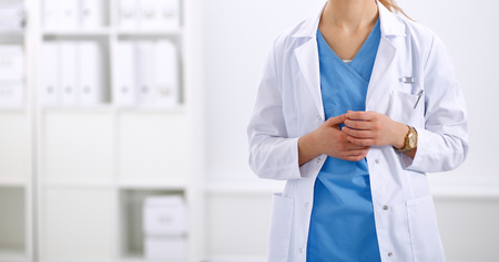 Portrait of young woman doctor with white coat standing in hospitalの写真素材