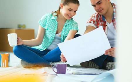 Man and woman looking at their house plans sitting in their new houseの写真素材
