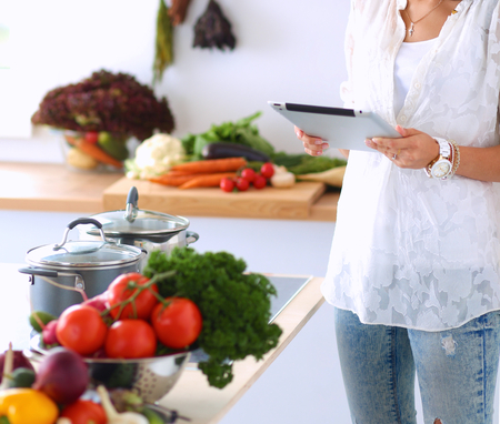 Young woman using a tablet computer to cook in her kitchen .の写真素材
