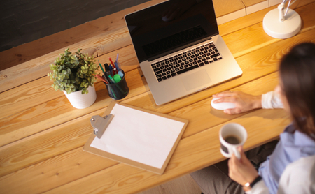 Portrait relaxed young woman sitting at her desk holding cup of coffee.の写真素材