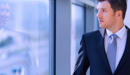 Successful businessman standing in hallway his company near windowの写真素材