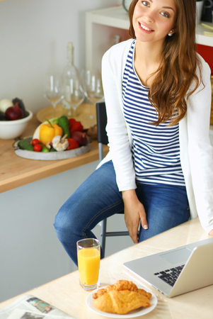 Young woman sitting near desk in the kitchenの写真素材