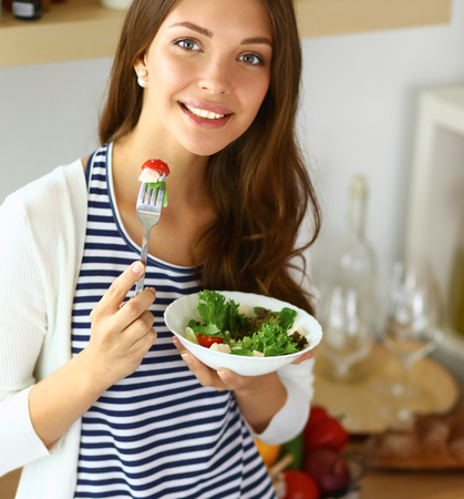 Young woman eating salad and holding a mixed saladの写真素材