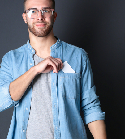 Man holding a credit card, isolated on black background.の写真素材