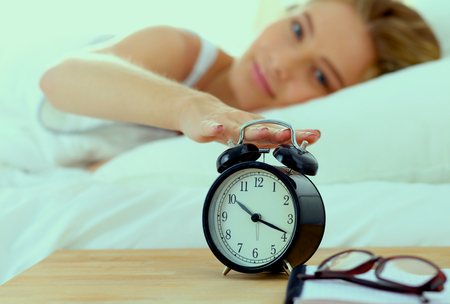 Young sleeping woman and alarm clock in bedroom at home.の写真素材