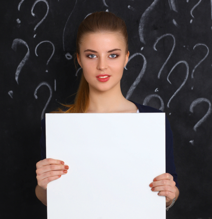 Young girl with question mark holding a blank on gray background.の写真素材