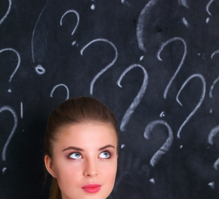 Young girl with question mark on a gray background.の写真素材
