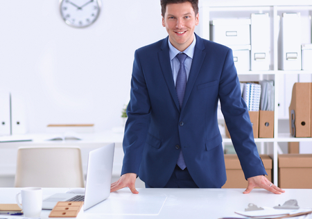 Confident successful young businessman leaning arms on his desk isolatedの写真素材