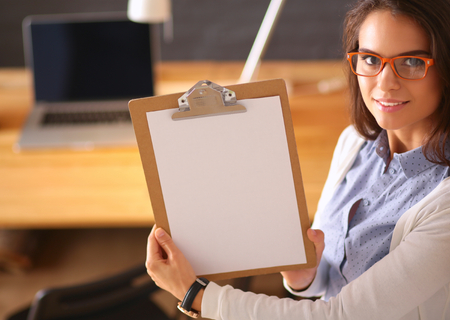 Young woman standing near desk with laptop holding folder.の写真素材