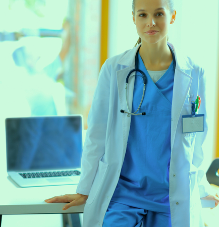 Woman doctor standing at hospital near desk.の写真素材
