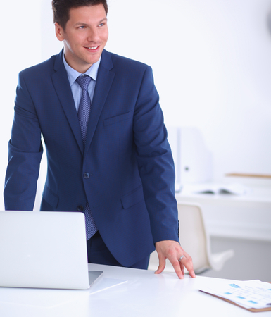 Business man or manager standing against his desk at the office isolatedの写真素材