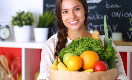 Young woman holding grocery shopping bag with vegetables.の写真素材