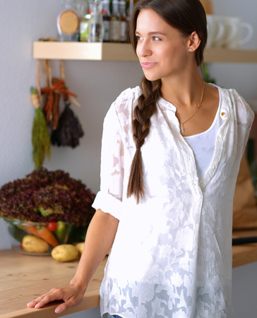 Young woman standing near desk in the kitchenの写真素材