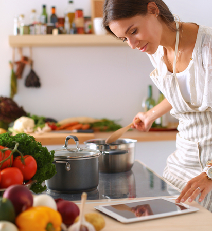 Young woman using a tablet computer to cook in her kitchen .の写真素材