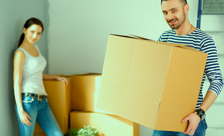 Happy young couple with boxes in new flatの写真素材