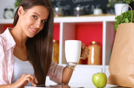 Young woman using a tablet computer to cook in her kitchen .の写真素材