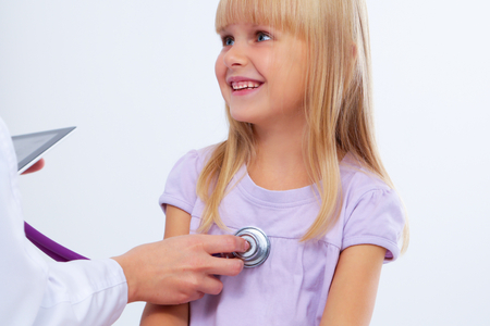 Female doctor examining child with stethoscope at surgery,isolatedの写真素材