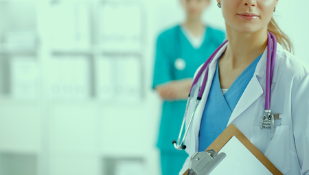 Woman doctor standing with folder at hospital.の写真素材
