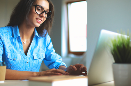 Young woman sitting in office table, looking at laptop computer screen .の写真素材