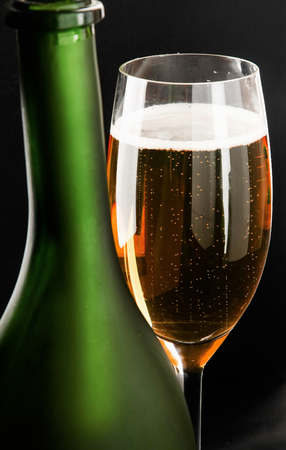 A glass of wine and a bottle on black background.の写真素材