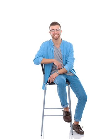 Young man sitting on the chair isolated over white background.の写真素材