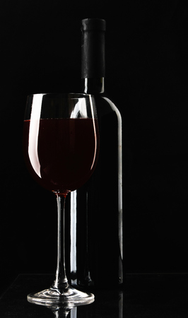 A glass of wine and a bottle on black background.の写真素材