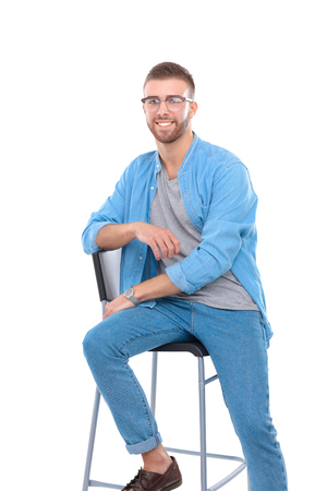 Young man sitting on the chair isolated over white background.の写真素材