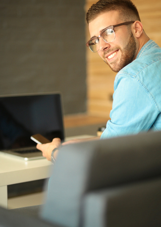 Young man using phone and works on the laptop.の写真素材