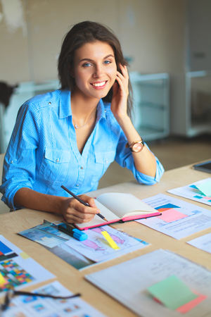 Young woman sitting at the desk with instruments, plan and laptop.の写真素材