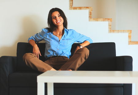 Portrait of happy young woman sitting on sofa.の写真素材