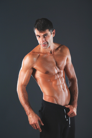 Strong athletic man standing on black background.の写真素材