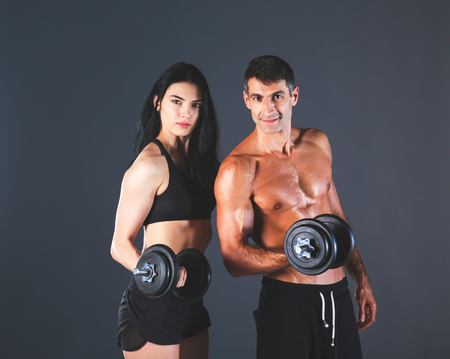Athletic man and woman with a dumbells.の写真素材