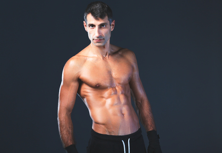 Strong athletic man standing on black background.の写真素材