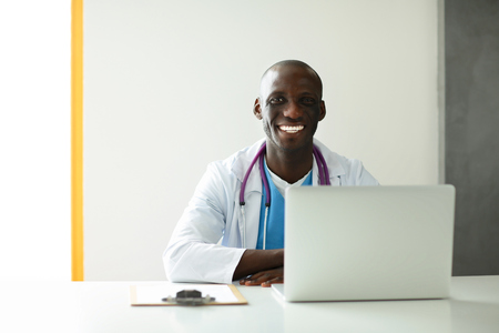 Young african doctor working on laptop at desk.の写真素材