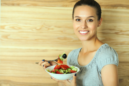 A beautiful girl eating healthy food on wooden backgroundの写真素材